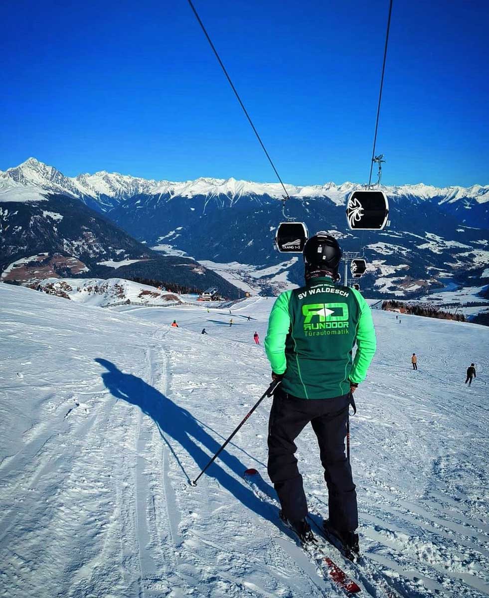 Mann mit Skihelm auf Skipiste und über sich den Sessellift